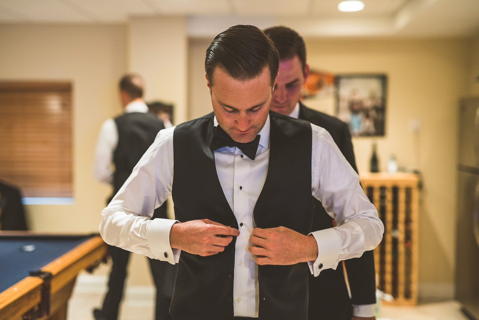 05 groom putting on vest - Kristina + Dave // Wedding Photographer in Chicago